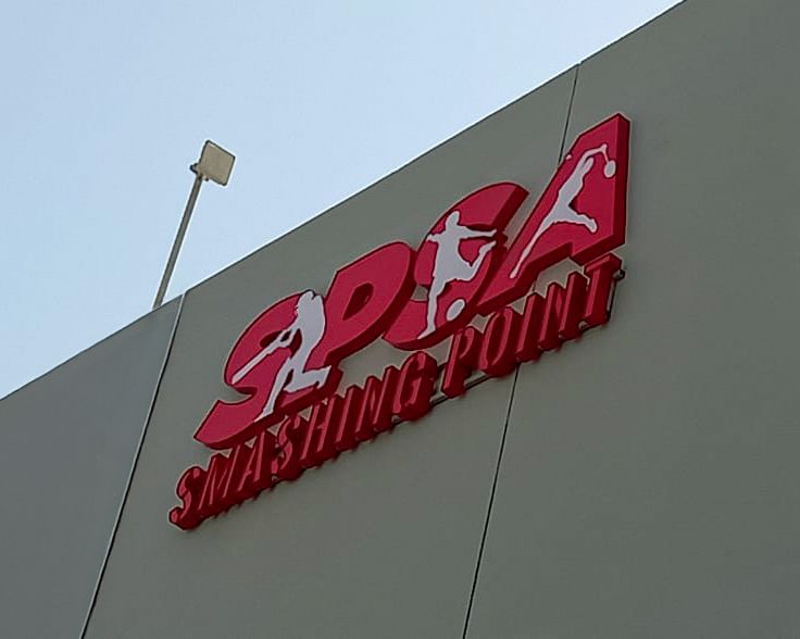 Red 3D logo sign for SPSA Smashing Point on building exterior